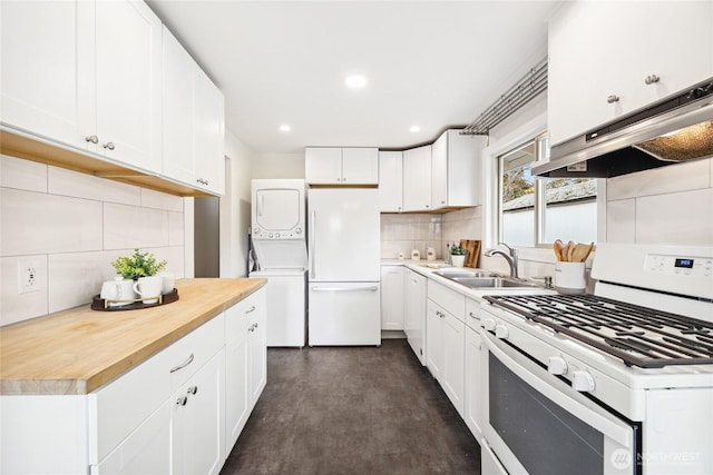 kitchen with stacked washer and dryer, decorative backsplash, range hood, white appliances, and a sink