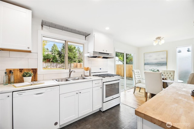 kitchen featuring under cabinet range hood, a sink, tasteful backsplash, white appliances, and light countertops