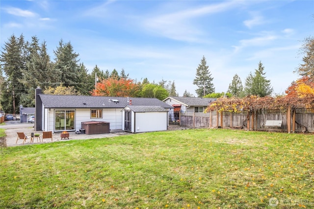 back of house featuring an outbuilding, a fenced backyard, a shed, and a hot tub