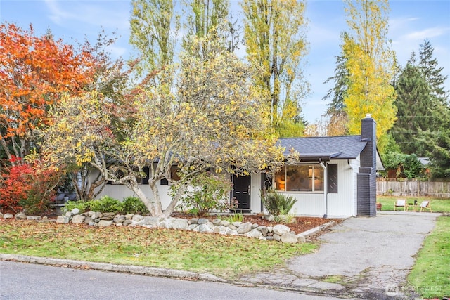 view of front of property featuring roof with shingles, a chimney, and fence