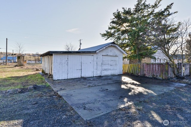 detached garage with concrete driveway and fence