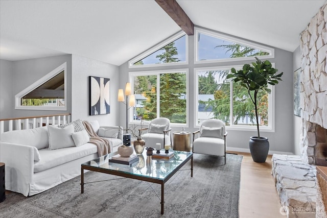 living area featuring lofted ceiling with beams, baseboards, wood finished floors, and a fireplace