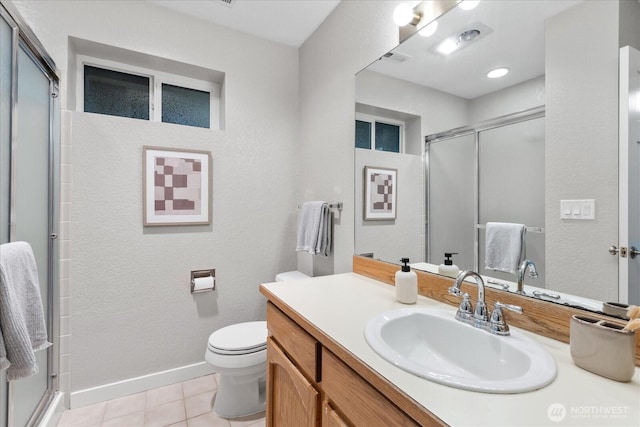 bathroom featuring toilet, a stall shower, tile patterned flooring, baseboards, and vanity