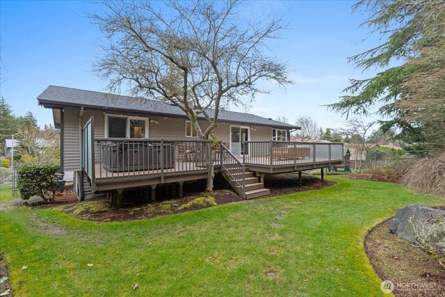 back of property with a lawn, a wooden deck, and fence