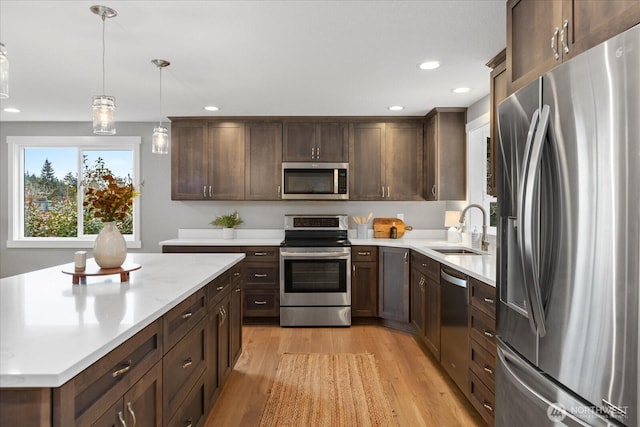 kitchen featuring light wood finished floors, recessed lighting, a sink, stainless steel appliances, and light countertops