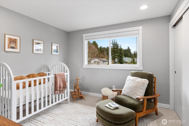 carpeted bedroom with baseboards and a nursery area