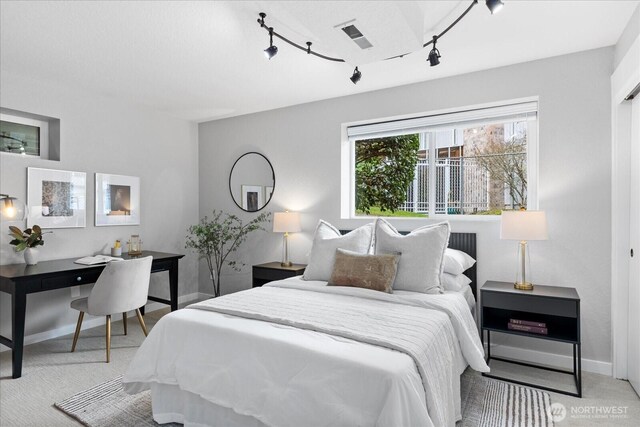 bedroom featuring visible vents, baseboards, light colored carpet, and track lighting