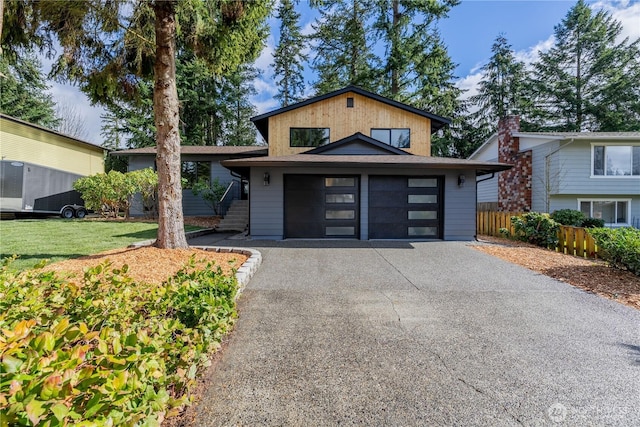 view of front of home with driveway, a front lawn, a garage, and fence