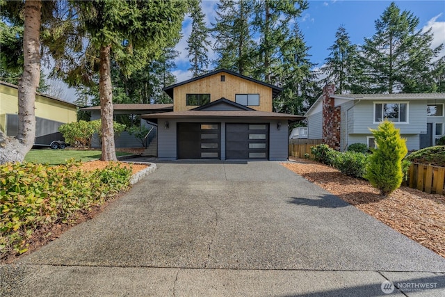 view of front of property with driveway, an attached garage, and fence