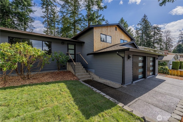 split level home with aphalt driveway, a garage, and a front lawn