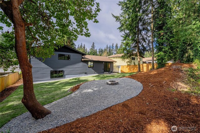 back of house featuring a fire pit, a yard, and fence