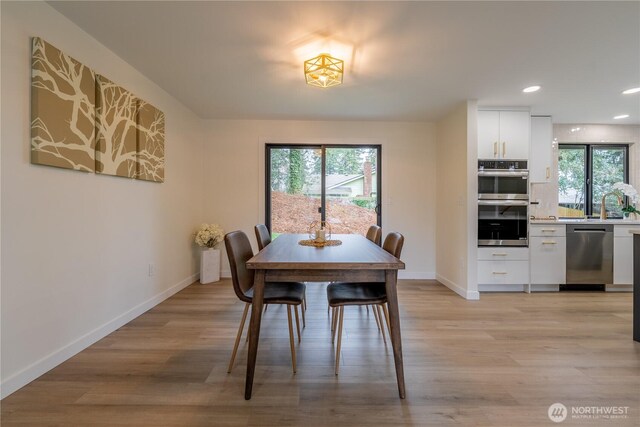 dining room with baseboards, plenty of natural light, and light wood-style flooring