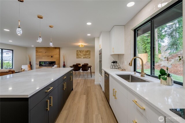 kitchen with white cabinetry, dark cabinets, open floor plan, and a sink