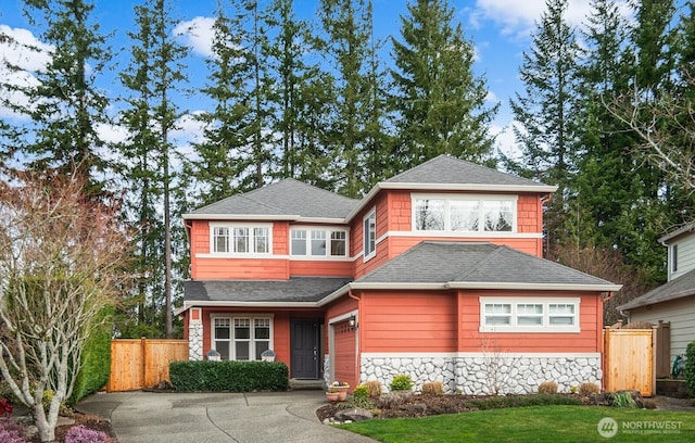 view of front of home featuring stone siding, driveway, a shingled roof, and fence