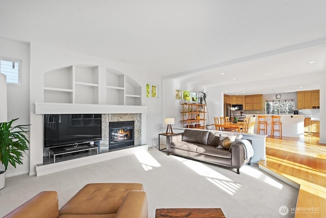 living area featuring a fireplace, built in features, light colored carpet, and recessed lighting