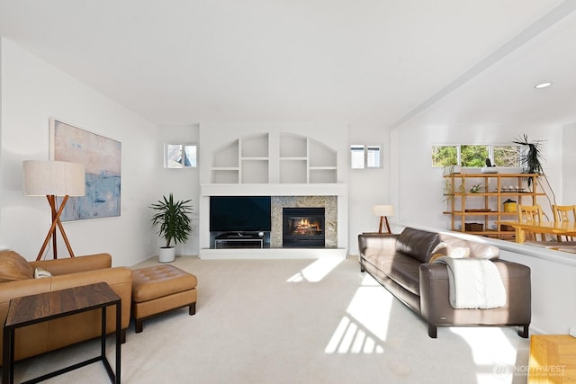 living room with built in features, a glass covered fireplace, and carpet flooring