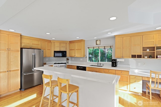 kitchen featuring light brown cabinets, light wood-style flooring, a sink, black appliances, and light countertops