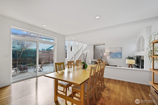 dining space featuring recessed lighting, a fireplace, stairs, and wood finished floors