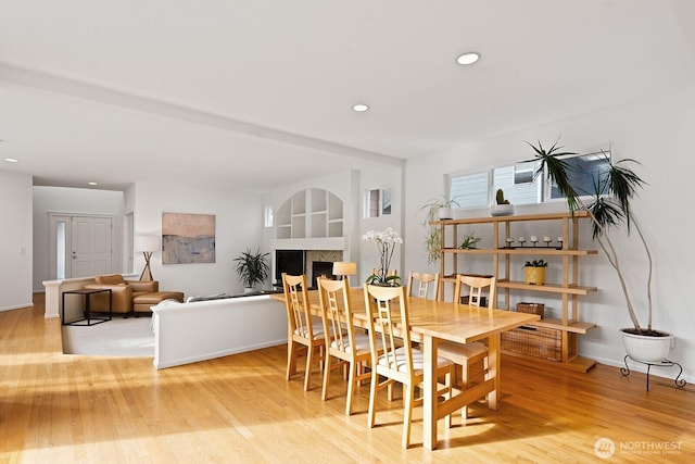 dining space featuring recessed lighting, a fireplace, light wood-type flooring, and baseboards