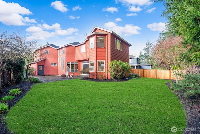 rear view of property featuring a patio, fence, and a lawn