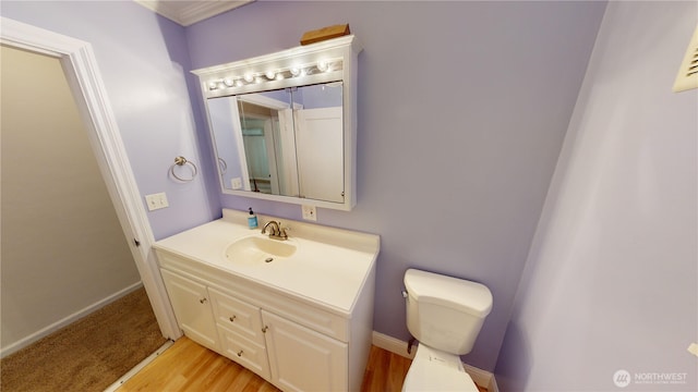 bathroom featuring baseboards, toilet, wood finished floors, and vanity