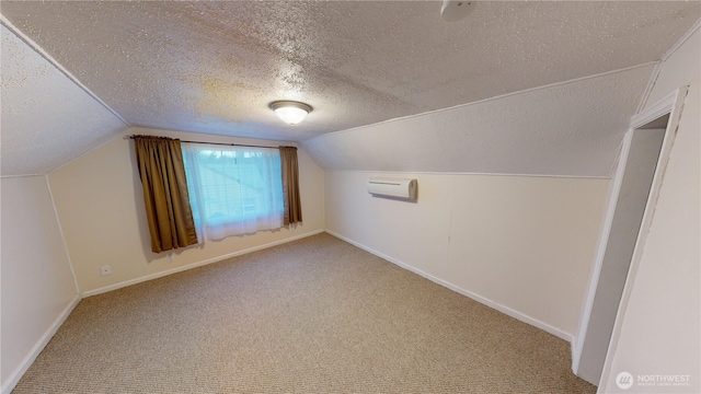 additional living space featuring baseboards, a wall mounted AC, lofted ceiling, a textured ceiling, and carpet flooring