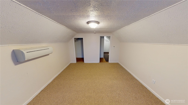 bonus room featuring baseboards, carpet, an AC wall unit, vaulted ceiling, and a textured ceiling