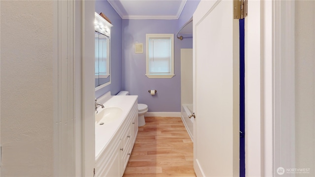 bathroom with baseboards, toilet, ornamental molding, wood finished floors, and vanity