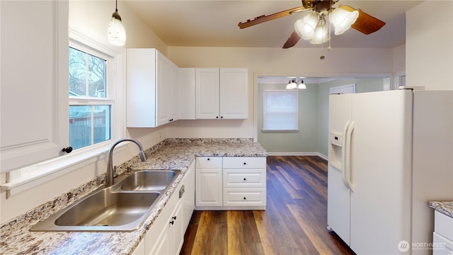 kitchen with pendant lighting, white fridge with ice dispenser, dark wood-style floors, white cabinetry, and a sink