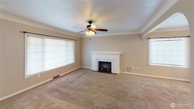 unfurnished living room with visible vents, a fireplace with flush hearth, ceiling fan, a textured ceiling, and carpet flooring