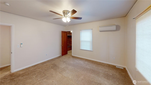 carpeted spare room featuring a wall unit AC, crown molding, a ceiling fan, and baseboards