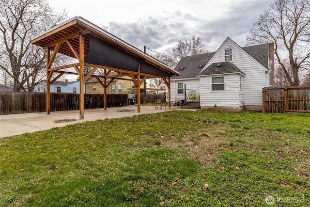 back of house featuring a yard, a shingled roof, a fenced backyard, and a patio area