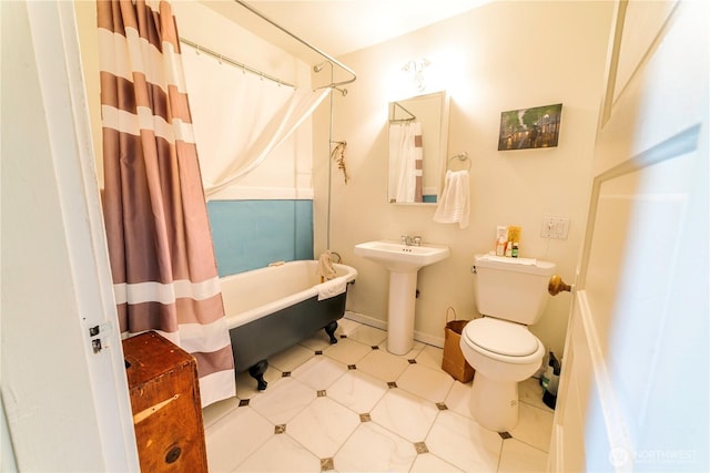 bathroom with toilet, shower / tub combo, baseboards, and a sink