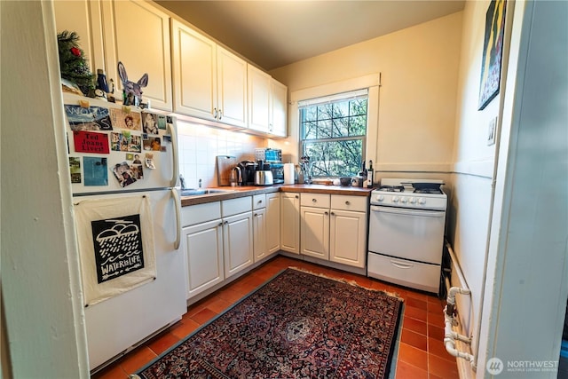 kitchen with white appliances, white cabinets, tasteful backsplash, and tile patterned floors