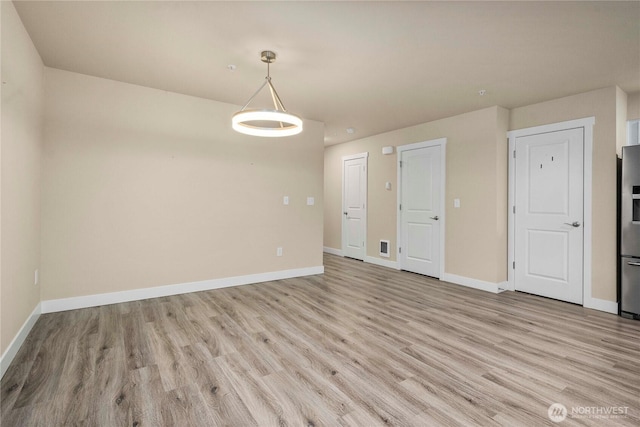 empty room featuring baseboards and light wood-style floors