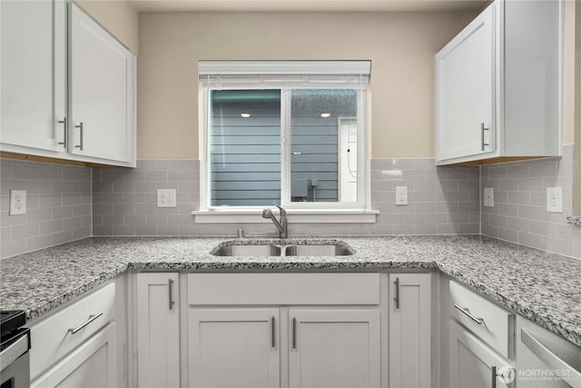 kitchen featuring tasteful backsplash, white cabinets, and a sink