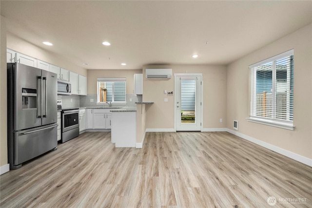 kitchen with tasteful backsplash, light wood-style flooring, stainless steel appliances, and a wall mounted AC