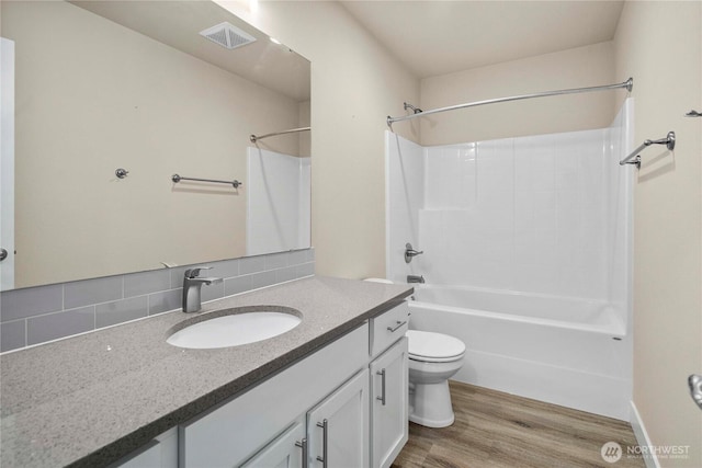 full bathroom with visible vents, tub / shower combination, toilet, wood finished floors, and vanity