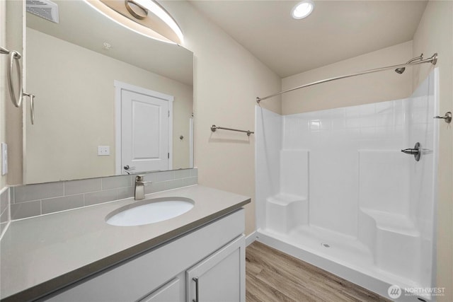 full bath with vanity, wood finished floors, a shower, and visible vents