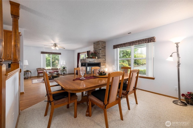 6084 Gartin Pl, Sedro Woolley, WA 98284 - dining area with a textured ceiling, a fireplace, light wood finished floors, baseboards, and ceiling fan