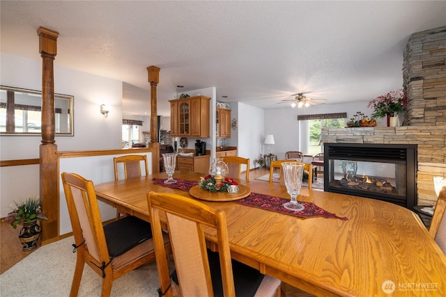 6084 Gartin Pl, Sedro Woolley, WA 98284 - dining room featuring a stone fireplace, a textured ceiling, a ceiling fan, and wood finished floors