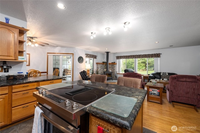 6084 Gartin Pl, Sedro Woolley, WA 98284 - kitchen featuring electric range, open floor plan, a center island, ceiling fan, and a wood stove