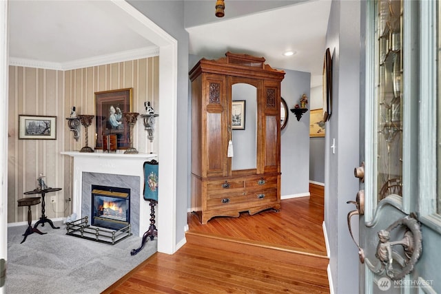 entryway with baseboards, wood finished floors, a high end fireplace, and ornamental molding