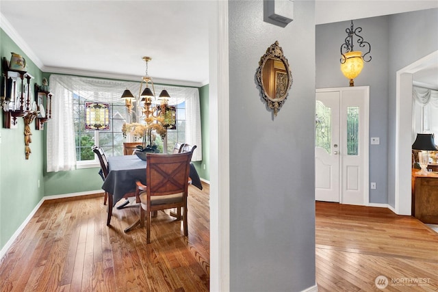 dining room featuring baseboards, an inviting chandelier, ornamental molding, and hardwood / wood-style flooring