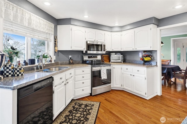 kitchen with a sink, stainless steel appliances, a wealth of natural light, and light wood-style flooring