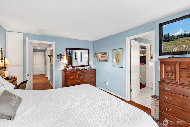 bedroom featuring ensuite bath, baseboards, and wood finished floors