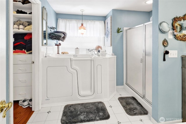 full bath featuring a bath, a stall shower, and a walk in closet