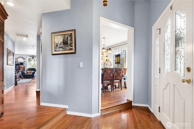 foyer entrance featuring visible vents, baseboards, and wood finished floors