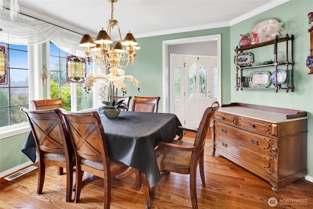 dining space with visible vents, crown molding, and wood finished floors