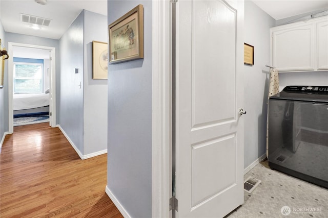 hallway featuring visible vents, washer / clothes dryer, light wood-style floors, and baseboards